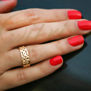Gold ring with intricate Celtic knot design worn on hand