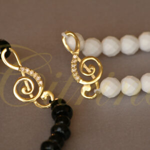 Handmade bracelets with gold spiral charms and black or white beads.