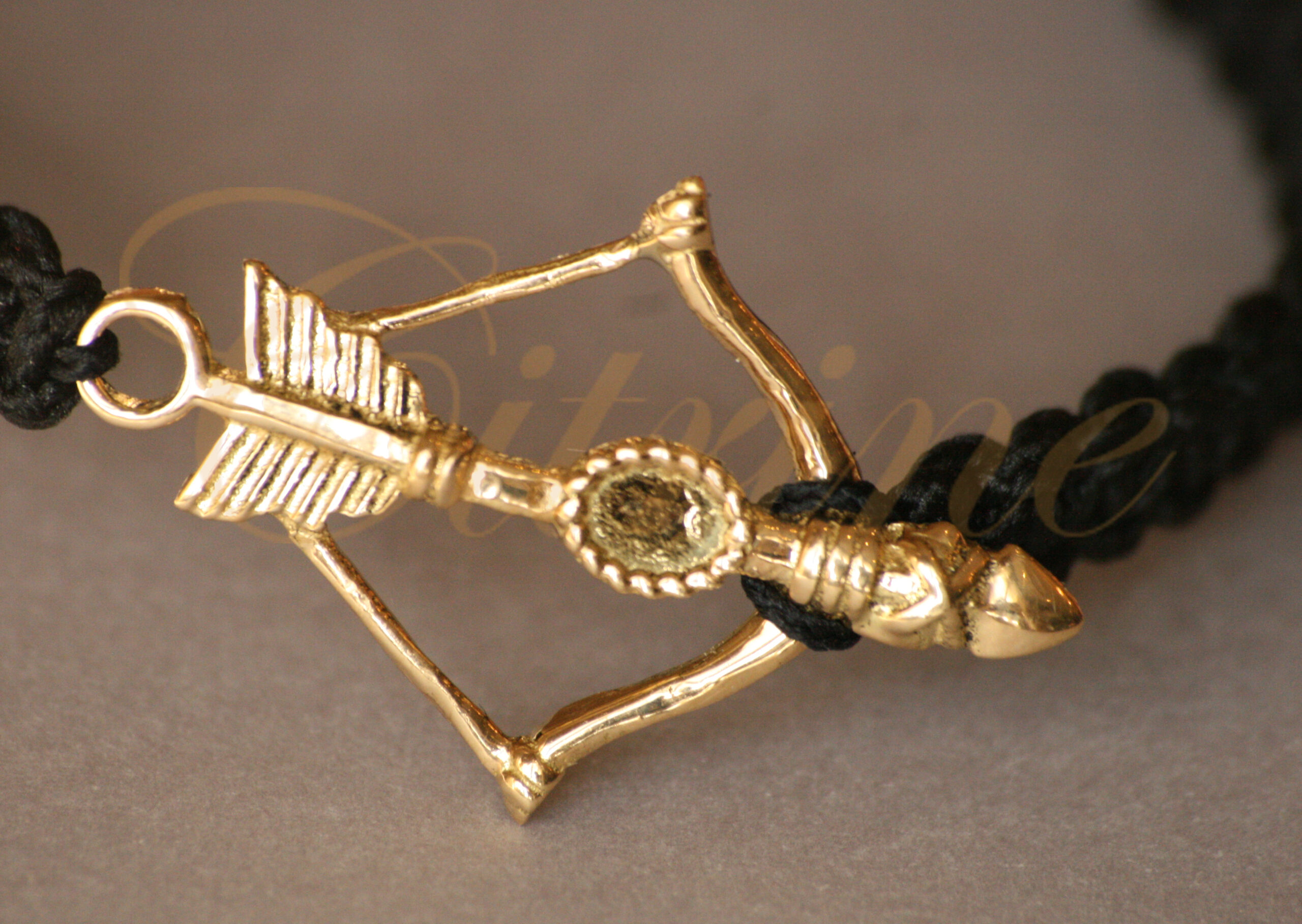 Handmade bracelet with gold-tone bow and arrow charm.